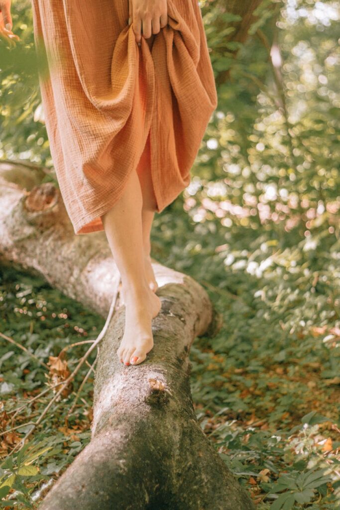 self-support, woman in a dress walking barefoot on a tree log