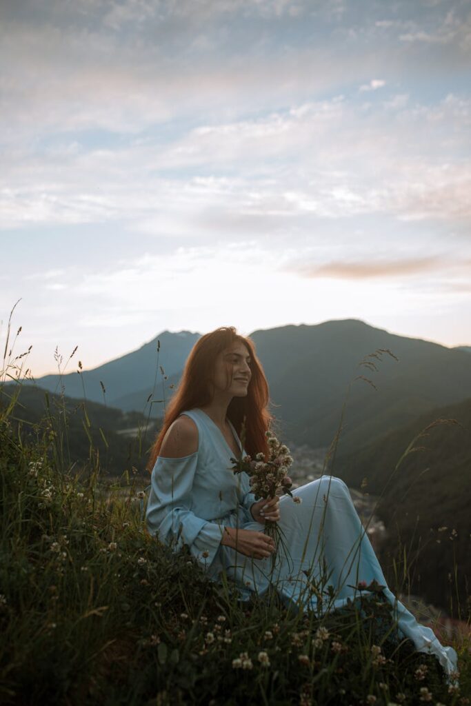 glow up,woman in white long sleeve shirt sitting on green grass field