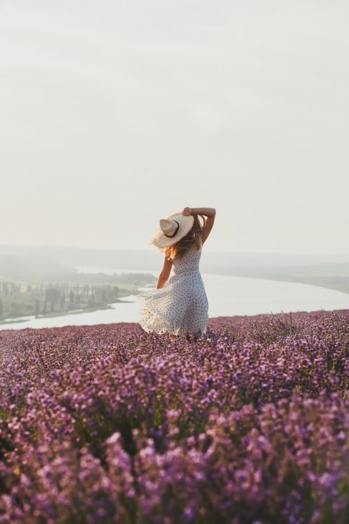woman in hat on meadow with flowers