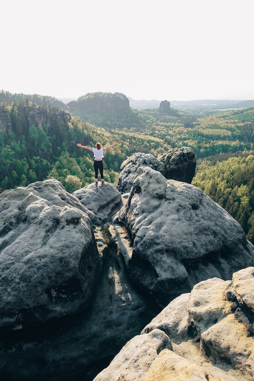 woman standing on rock formation in elbe sandstone mountains in germany. letting go