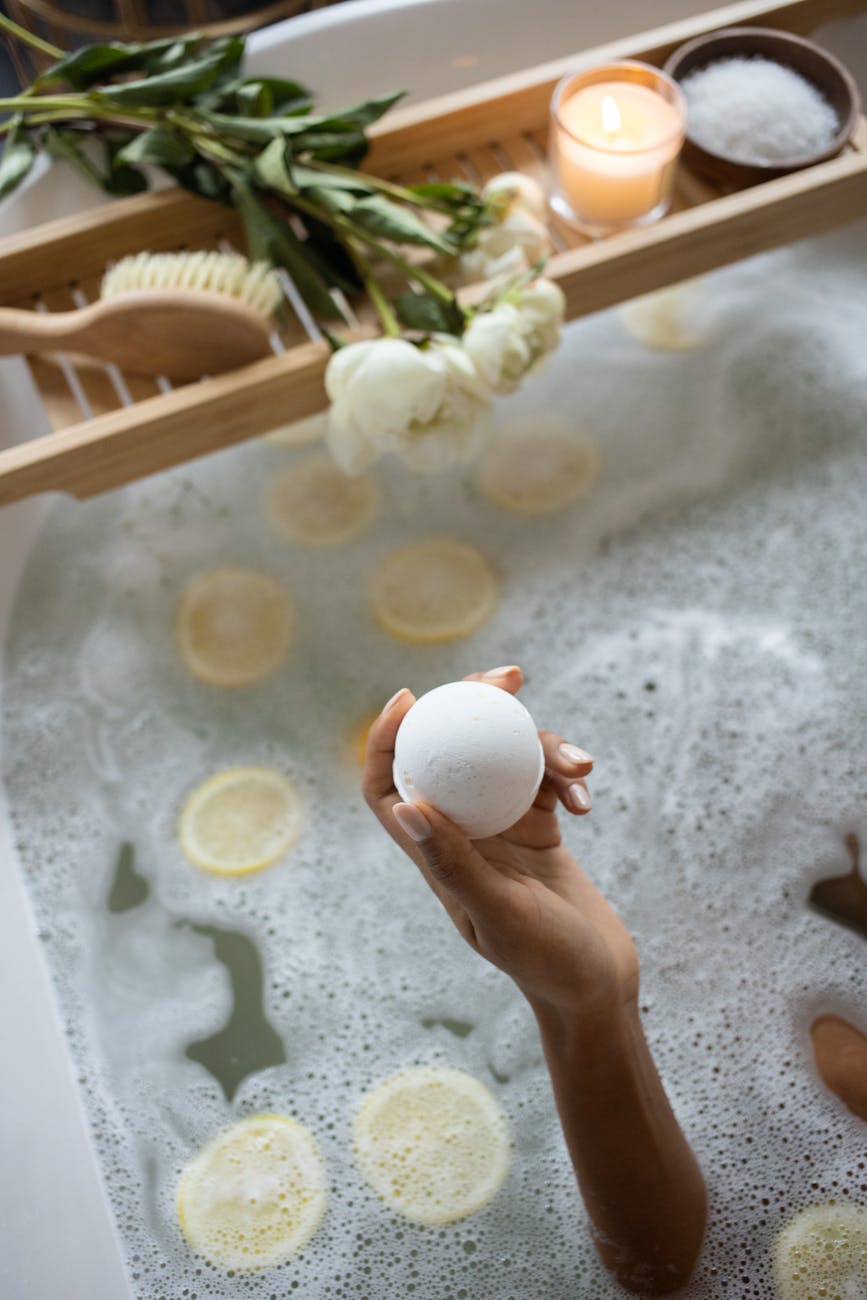 crop woman with bath bomb sitting in tub. self-support