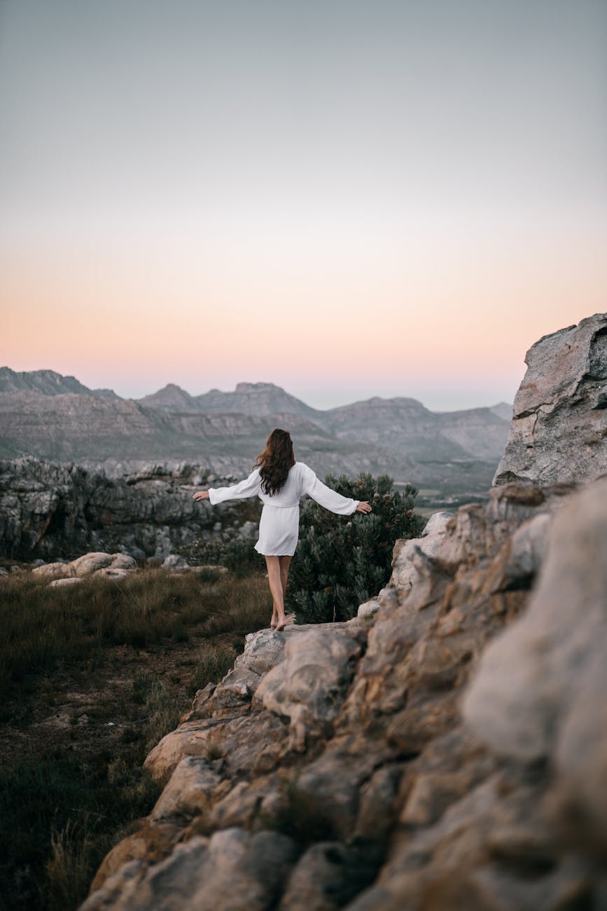 woman in white long sleeves dress on a rocky mountain