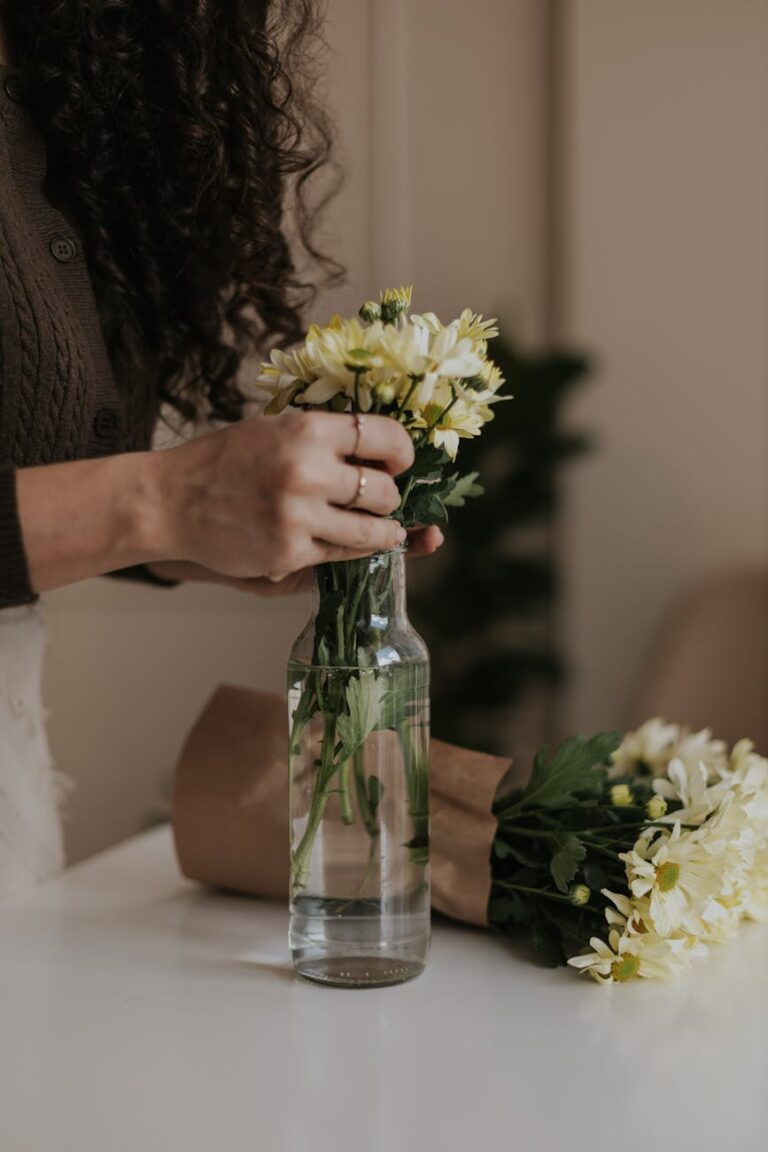 woman arranging yellow flowers in glass vase
